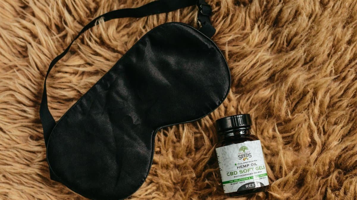 CBD soft gels and black eye mask laid on brown fur promoting relaxation and sleep.