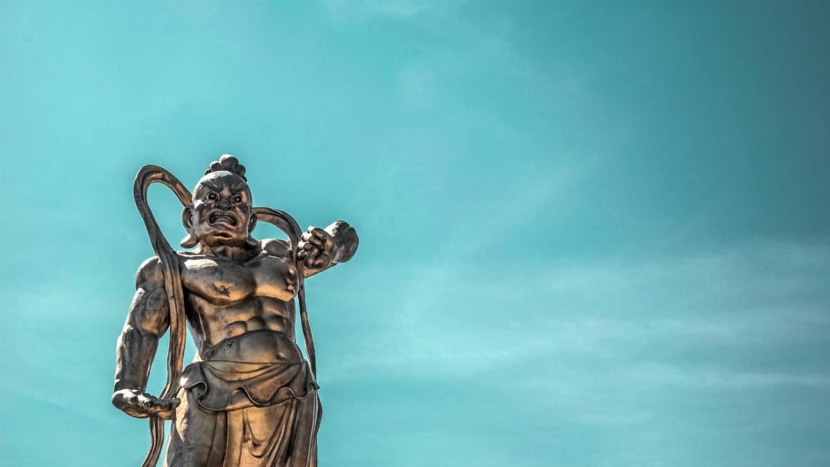 A striking bronze statue of an ancient warrior with a deep blue sky backdrop.