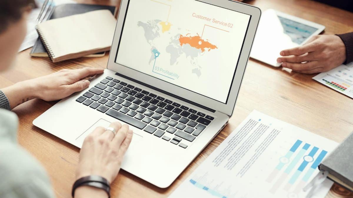 Professional team discussing global marketing strategies with charts and graphs on a laptop.