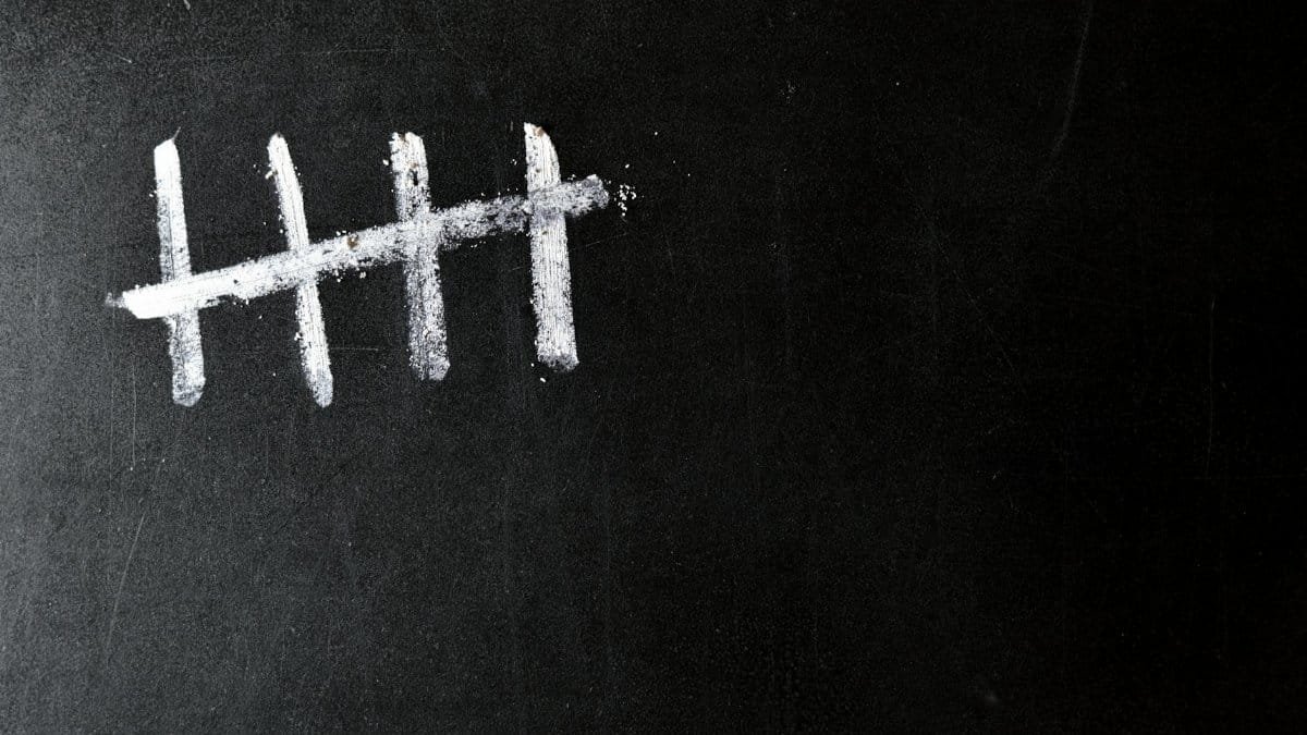 Five chalk tally marks on a black chalkboard background.