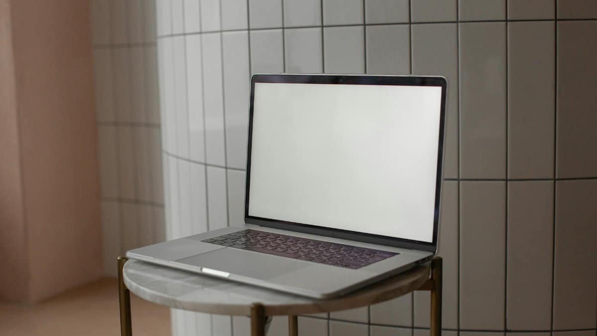 A sleek laptop with a blank screen on a round marble-top table indoors.