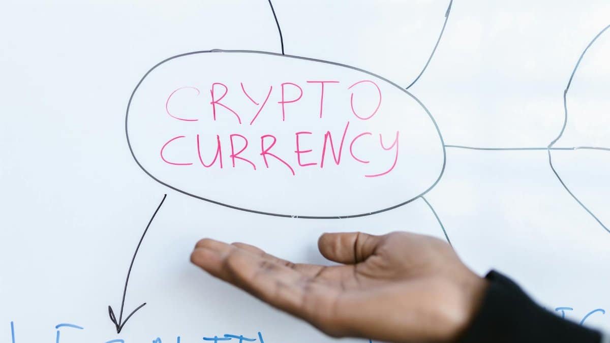Close-up of a hand gesturing at a cryptocurrency diagram on a whiteboard, highlighting crypto concepts.