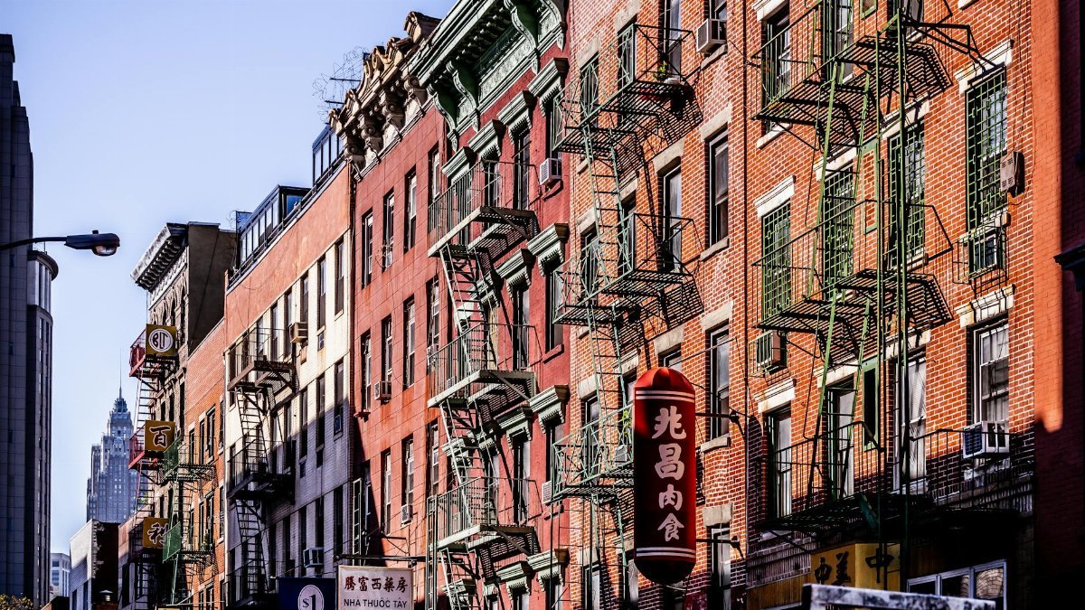 Colorful fire escape lined buildings in New York City's Chinatown vibrant street scene.