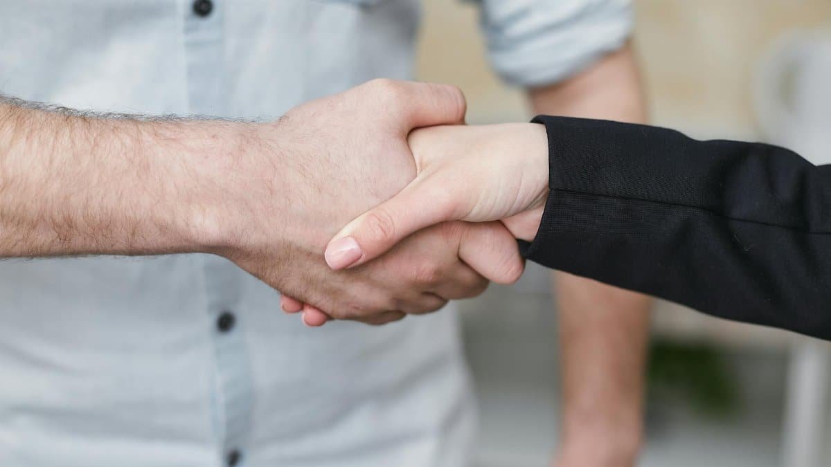 Close-up of two individuals shaking hands symbolizing business agreement and partnership.