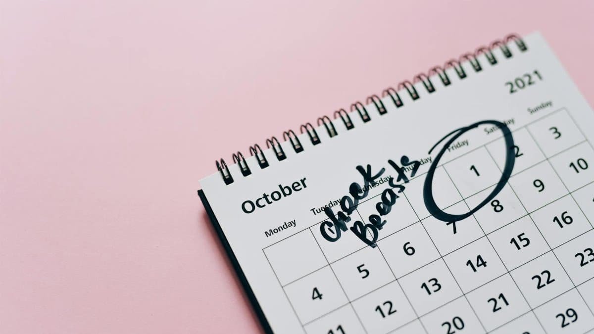 October calendar with breast check reminder, emphasizing health awareness on a pink background.