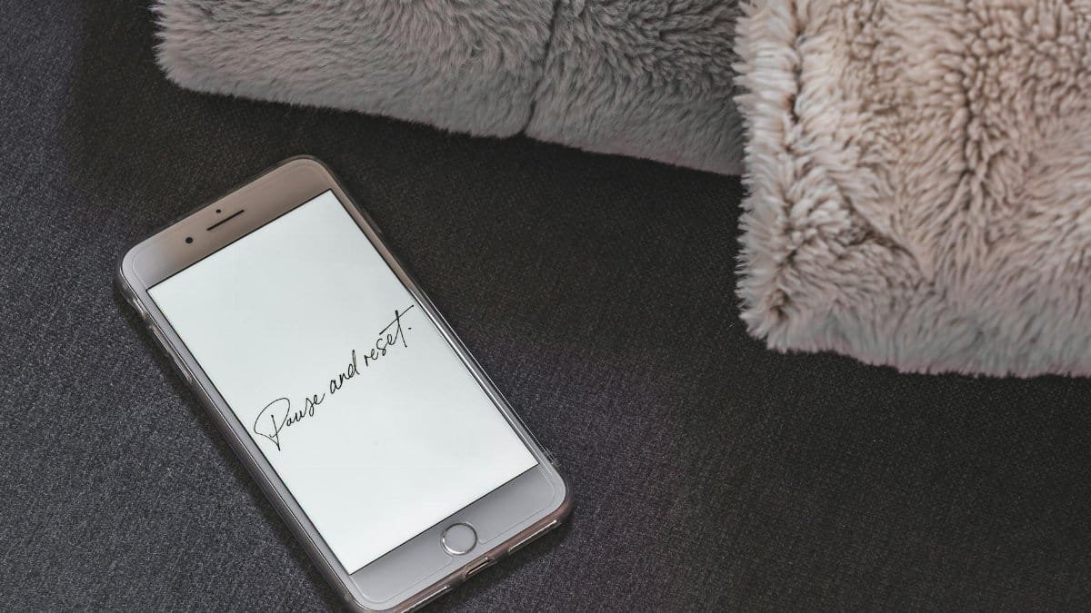 A smartphone on a soft surface showing 'Pause and Reset' on the screen.