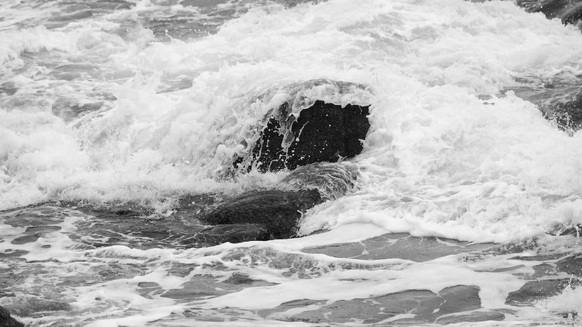 Monochrome sea waves crashing against rocks, offering a dramatic view of nature's power.