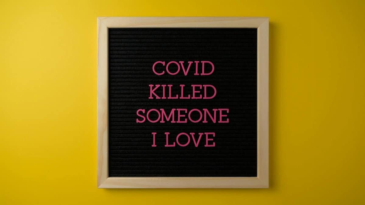 A heartfelt message about COVID loss displayed on a letter board against a yellow background.