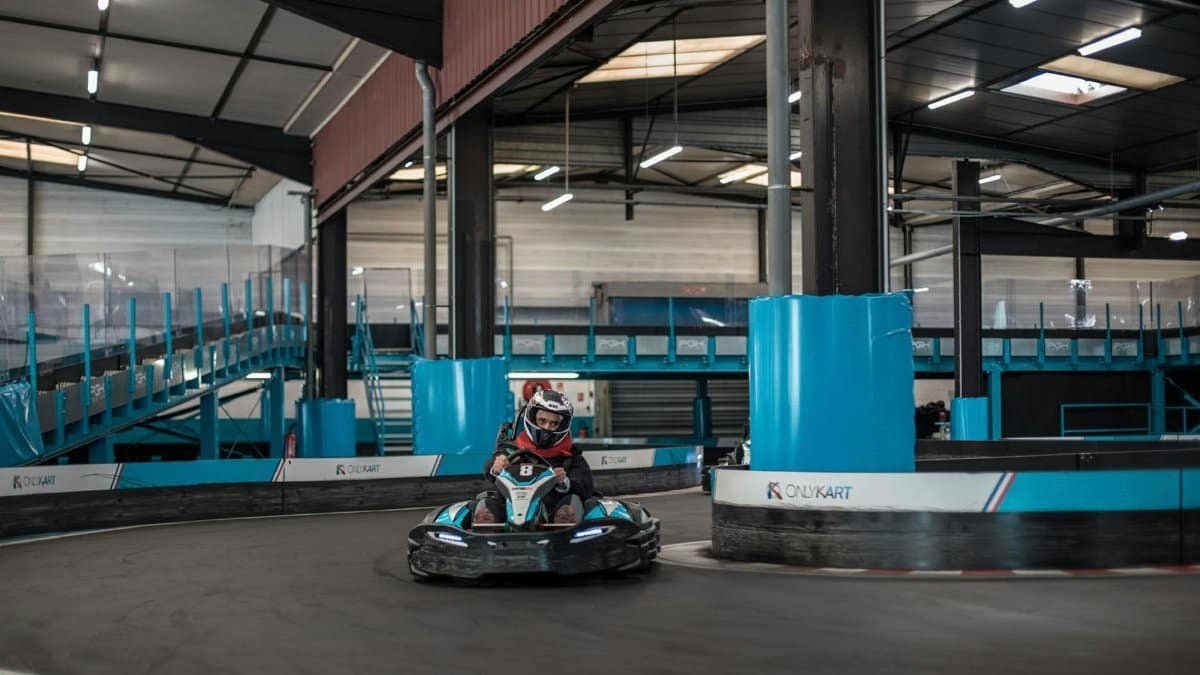 Exciting indoor go-kart racing scene with a racer navigating a sharp turn.