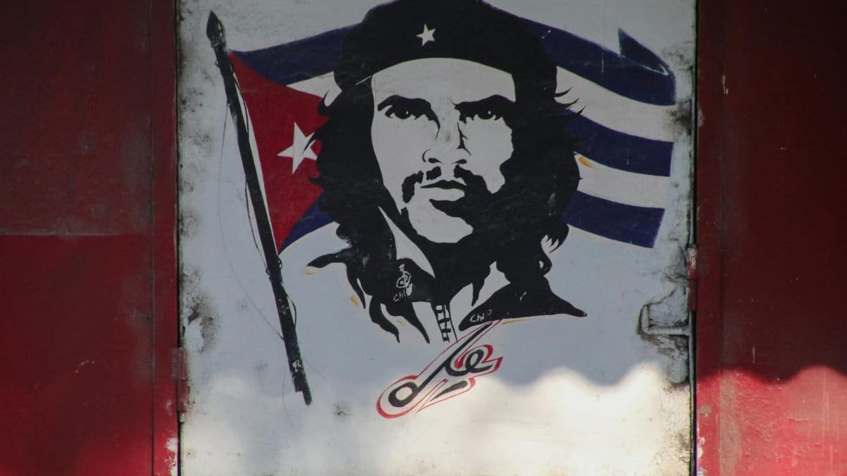 A mural of Che Guevara with a Cuban flag background painted on a wall.