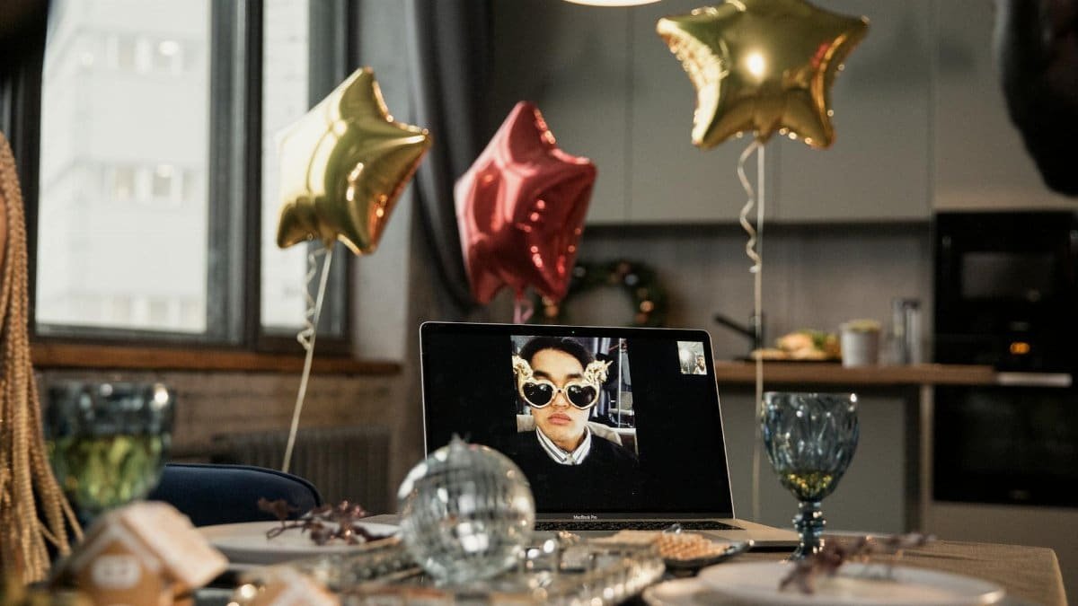 A lively Christmas party setup with star balloons and a laptop displaying a video call, embracing virtual festivities.