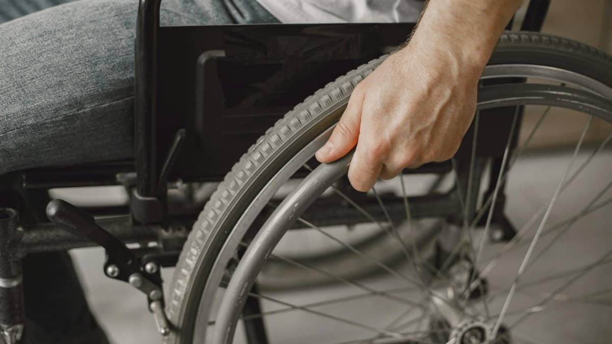 A close-up image showing a hand gripping a wheelchair wheel, portraying mobility and accessibility.