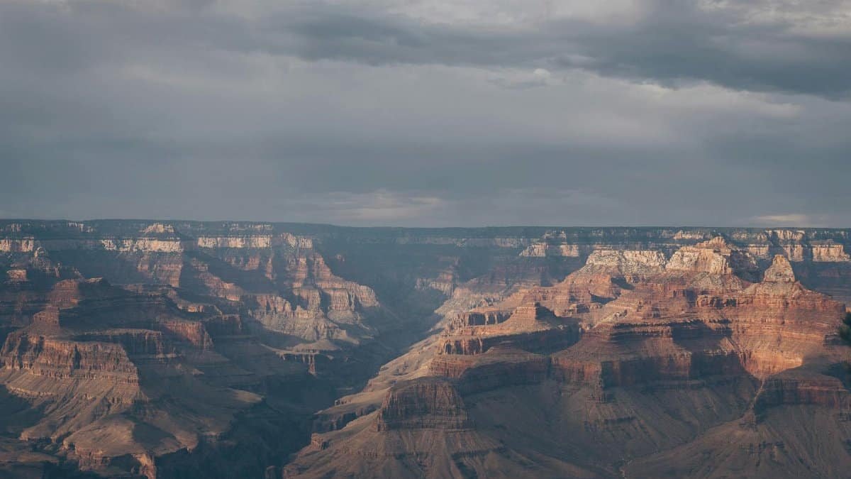 A stunning view of the Grand Canyon with dramatic lighting and moody skies, showcasing its majestic geology.