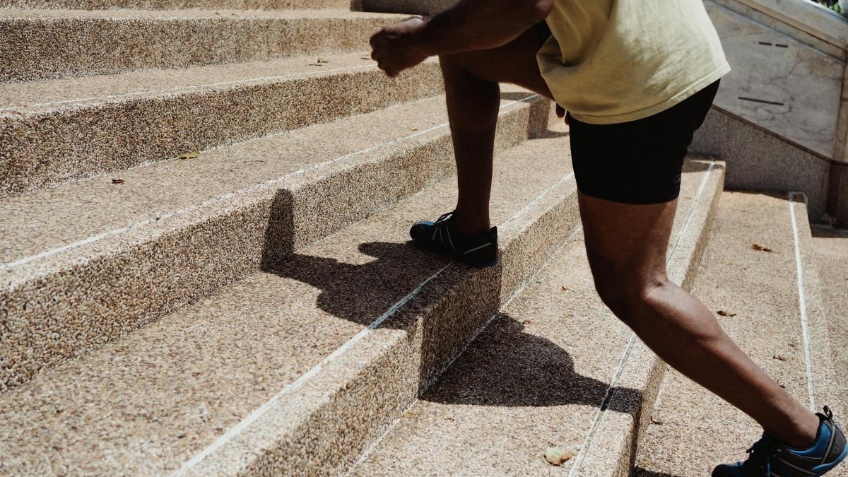 A man running up stone stairs outdoors, showcasing fitness and urban exercise.