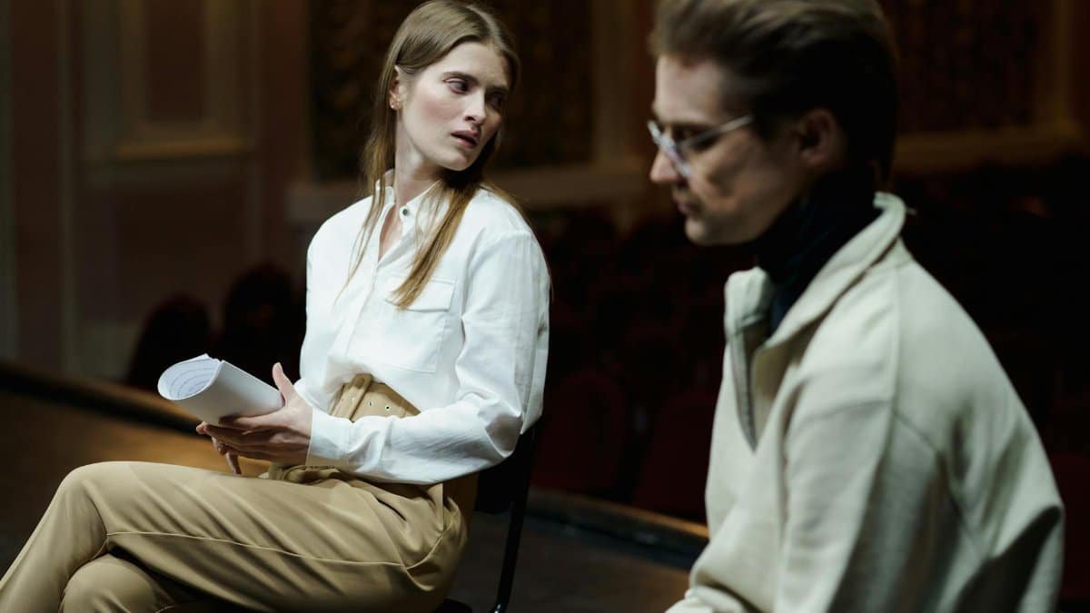 Two actors in a theater setting deeply engaged in a script rehearsal scene.