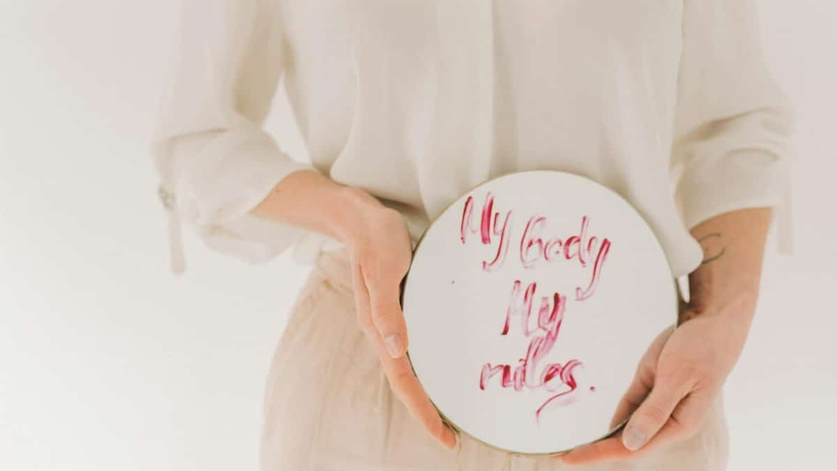 A woman holds a mirror with empowering feminist message 'My body, my rules.'