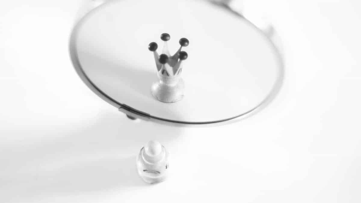 A creative black and white image showing a pawn's reflection as a crown, symbolizing self-perception.