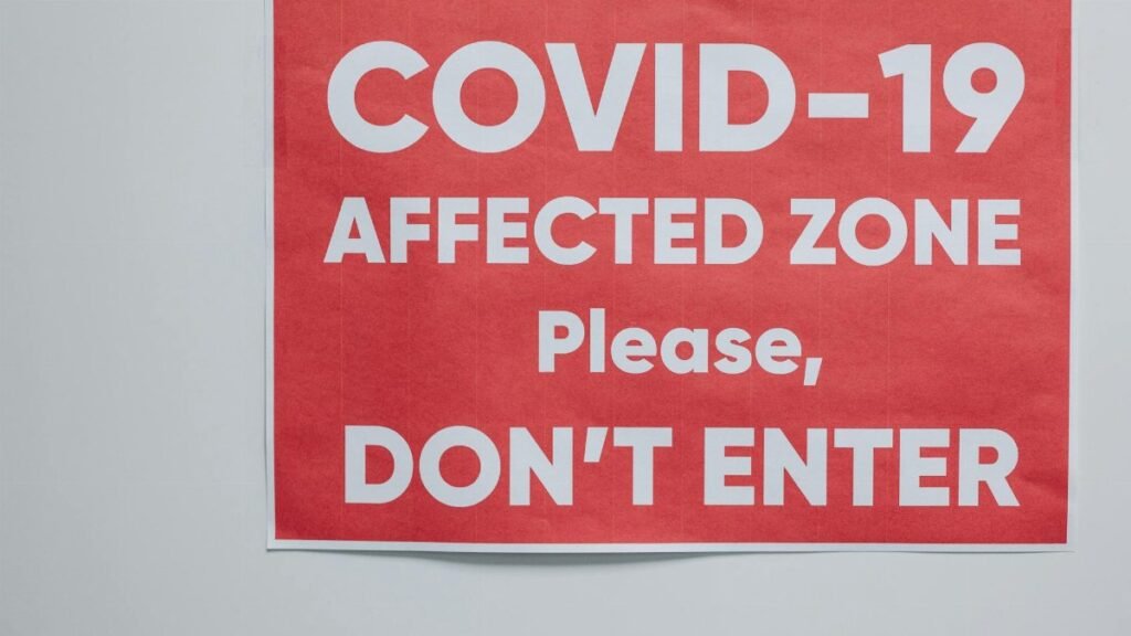 Red warning sign for COVID-19 affected area urging people not to enter.