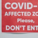 Red warning sign for COVID-19 affected area urging people not to enter.