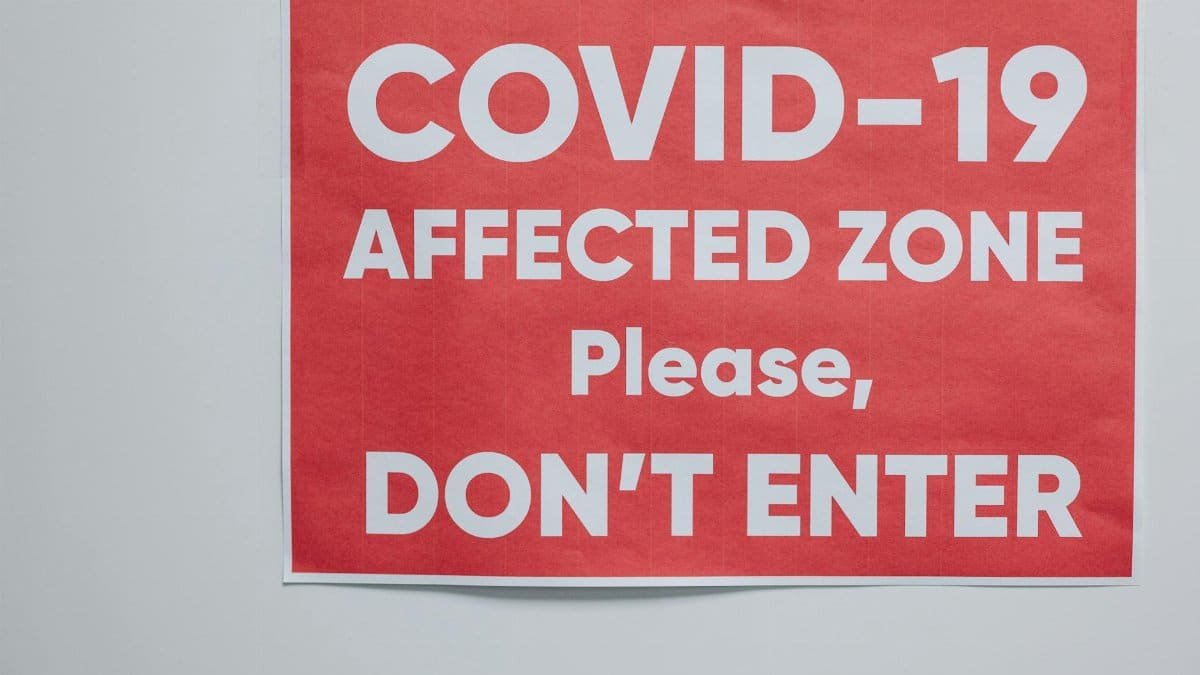 Red warning sign for COVID-19 affected area urging people not to enter.