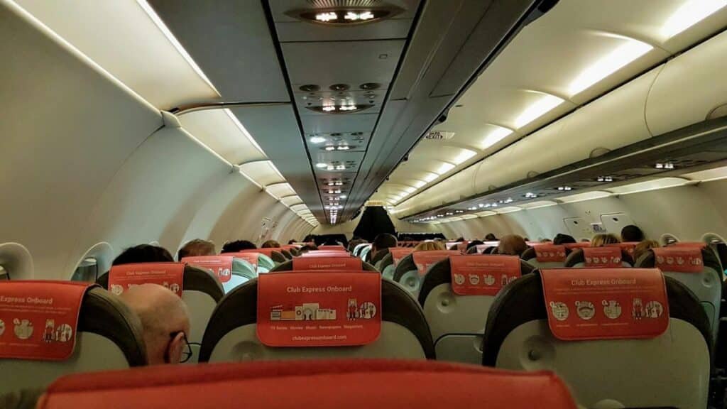 A look inside an airplane cabin filled with seated passengers during a flight.