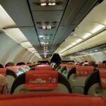 A look inside an airplane cabin filled with seated passengers during a flight.
