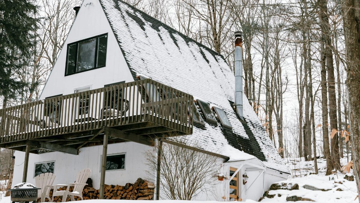 Charming A-frame cabin surrounded by snow-covered forest in winter, Stowe, Vermont.