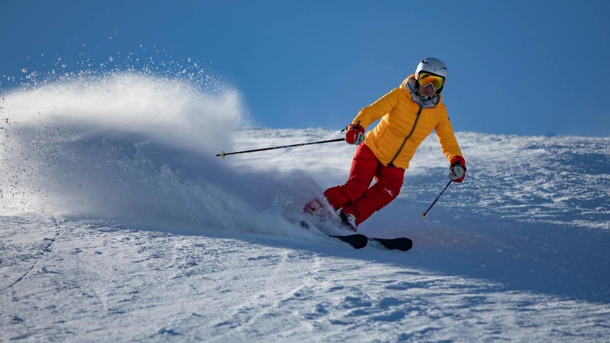 A skier wearing bright gear expertly navigates a snowy slope with speed and precision.