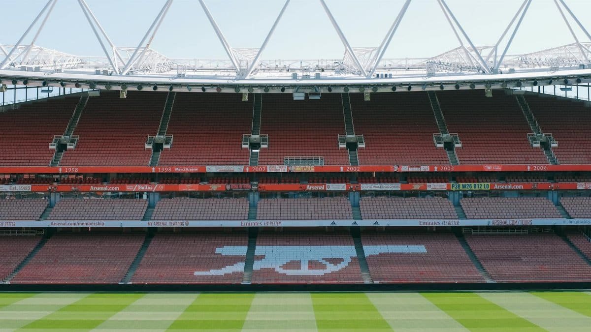 View of Arsenal's iconic Emirates Stadium with empty stands and lush football pitch.