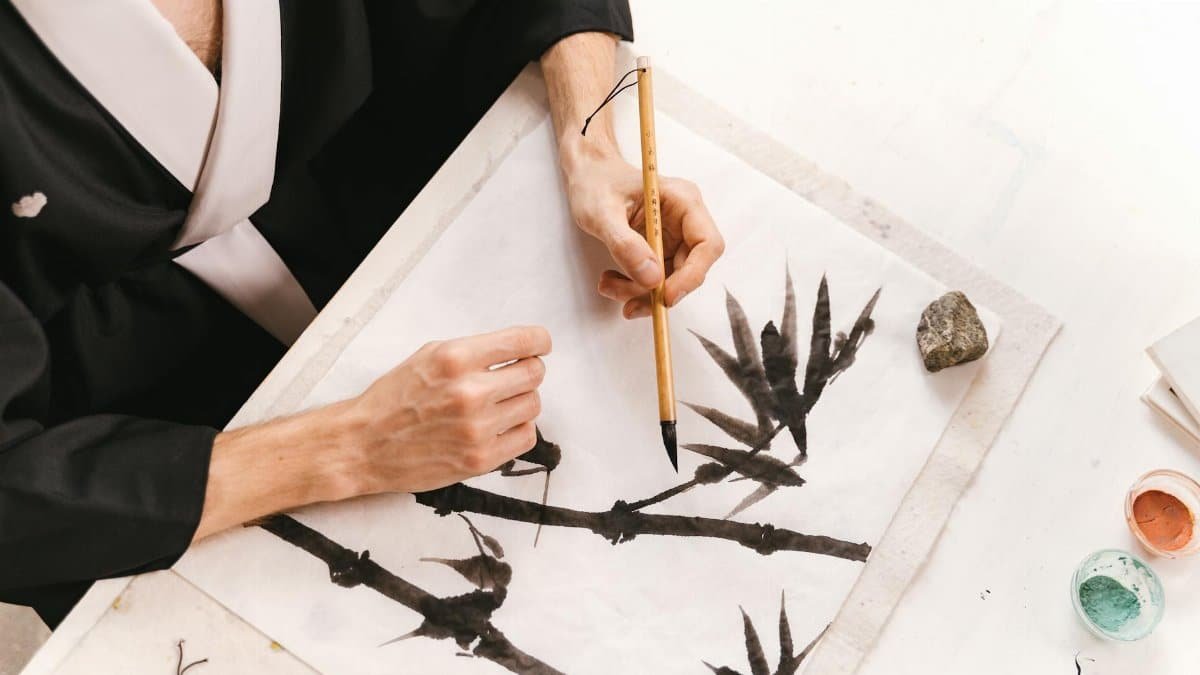 An artistic session capturing a person painting bamboo with a traditional Japanese ink brush on paper.