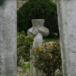 A weathered gravestone surrounded by stone columns in an ancient cemetery.