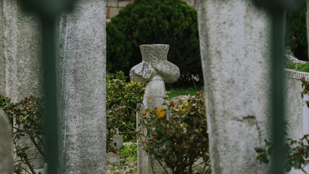A weathered gravestone surrounded by stone columns in an ancient cemetery.