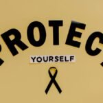 Conceptual awareness image with "Protect Yourself" text and black ribbon on yellow background.