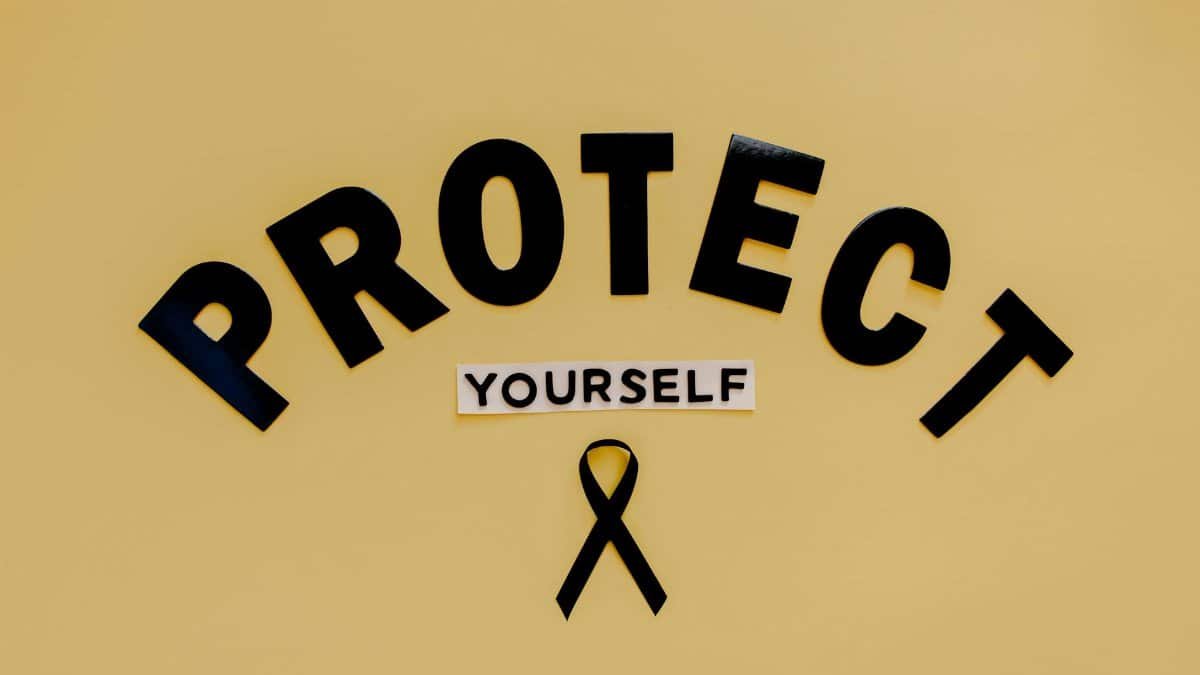 Conceptual awareness image with "Protect Yourself" text and black ribbon on yellow background.