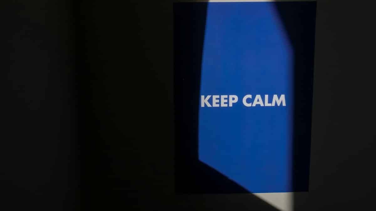 Blue poster with 'Keep Calm' text illuminated by spotlight in dark room.