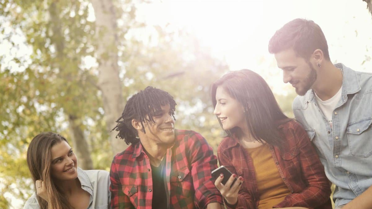 Group of young friends laughing and enjoying time together outdoors in a sunny park.
