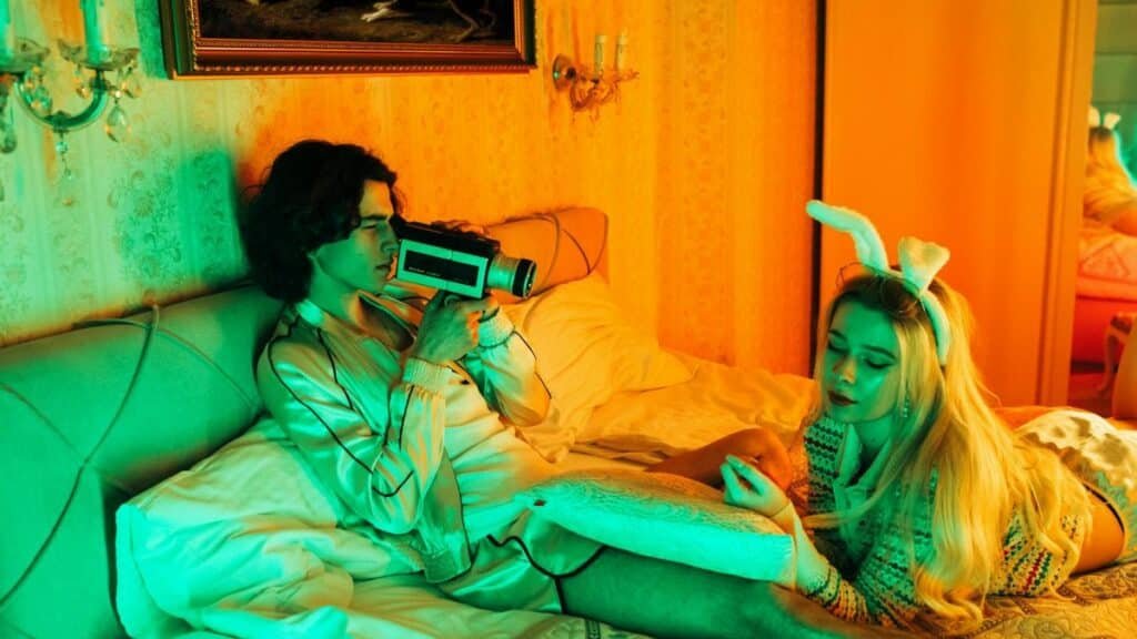 Stylish young couple in bed with retro camera and bunny ears, creating a vintage vibe.