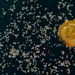 Close-up of a gold medal with blue ribbon and confetti on a black surface, symbolizing victory.