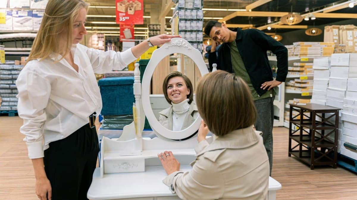 Group exploring furniture in store with mirror reflection and smiles.