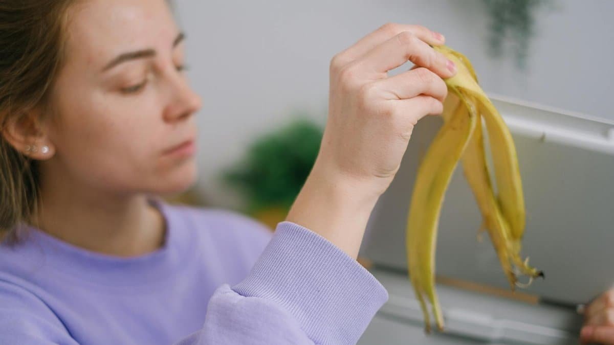 Close-up of a woman throwing a banana peel into a trash bin. Eco-friendly waste management.