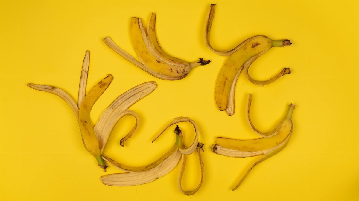 Artistic arrangement of banana peels on a vibrant yellow background, top view.