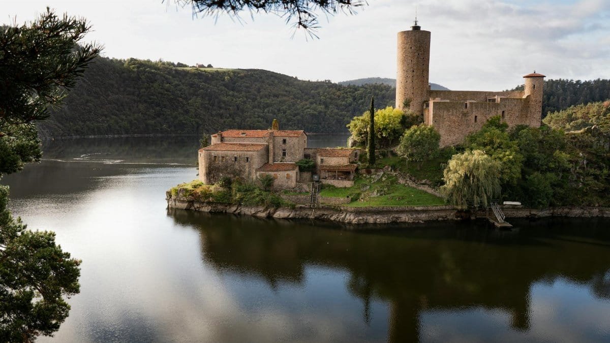 Picturesque view of Château de Grangent surrounded by serene waters in Auvergne-Rhône-Alpes.