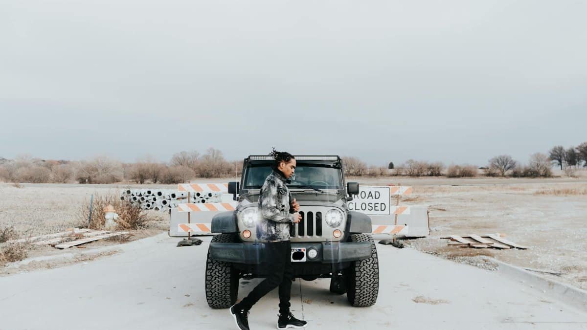 Young person poses confidently beside a Jeep on a closed road in Omaha, Nebraska.
