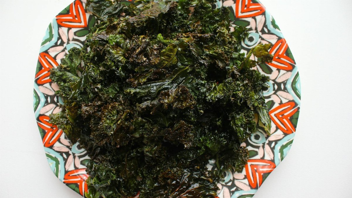 A vibrant dish of homemade kale chips served on a colorful plate.