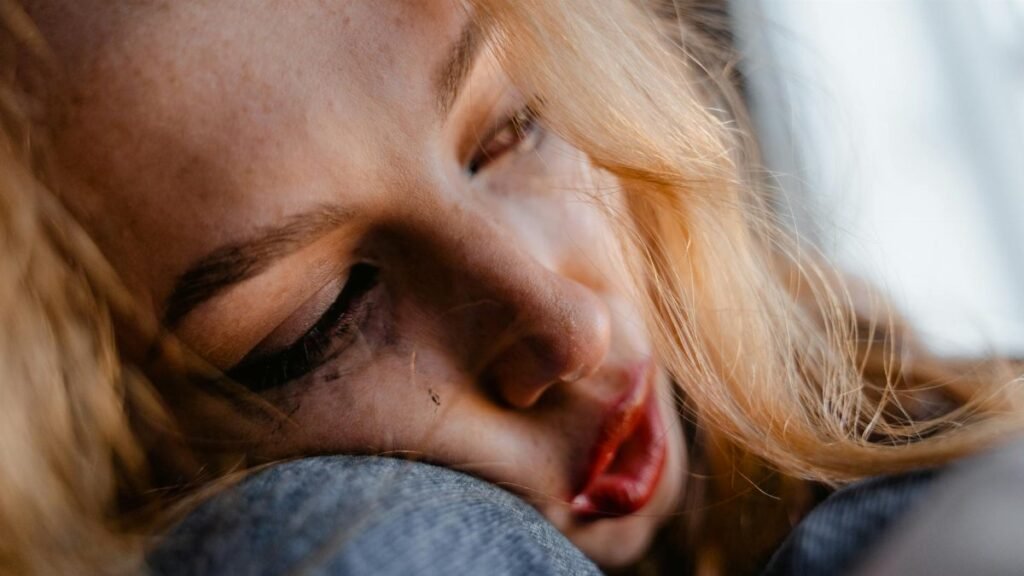 A close-up of a young woman resting her head, appearing thoughtful and introspective.