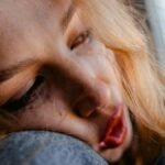 A close-up of a young woman resting her head, appearing thoughtful and introspective.