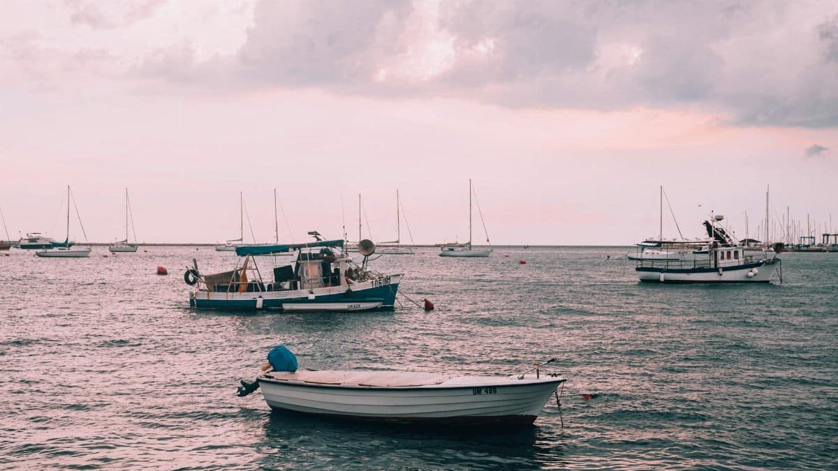 Serene image of fishing boats on calm sea under cloudy sky in Croatia.
