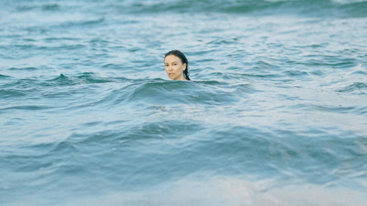 A serene moment of a woman swimming in the tranquil ocean, showcasing nature's beauty.