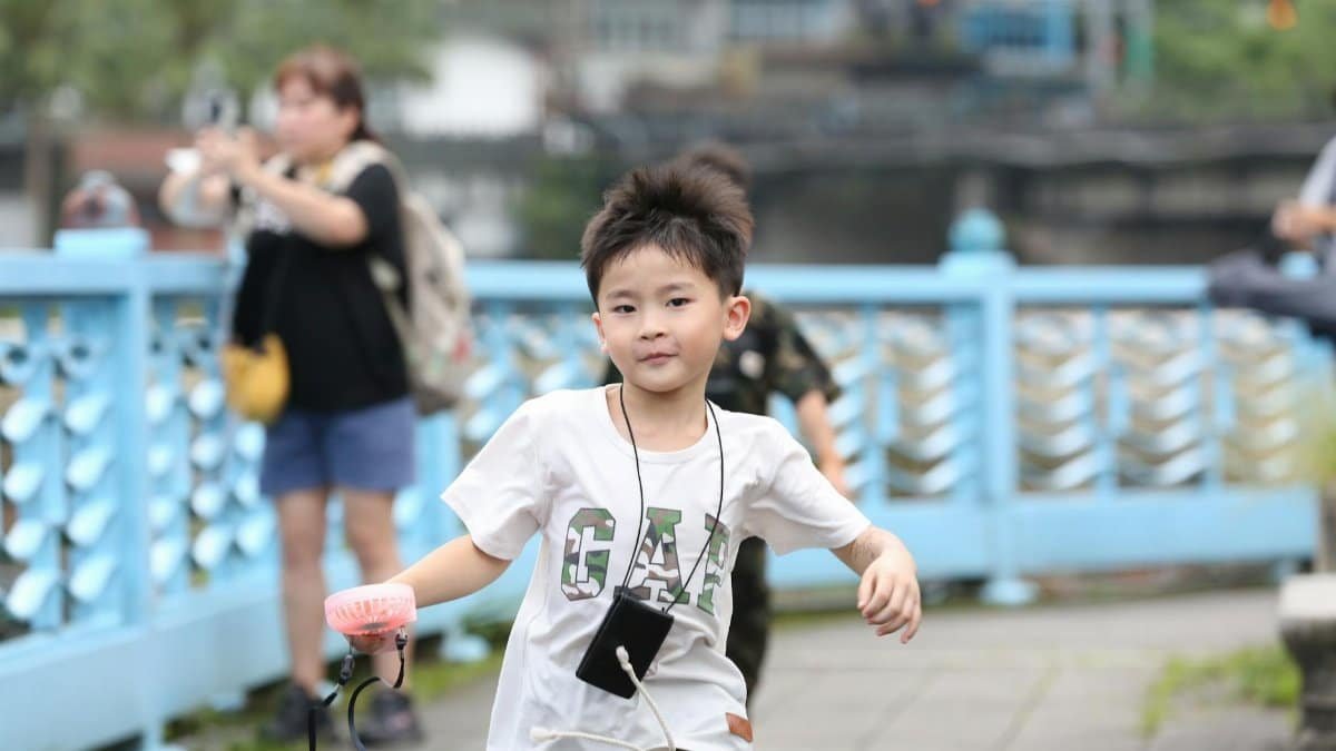 A cheerful boy running on a blue outdoor promenade, capturing a moment of joy.