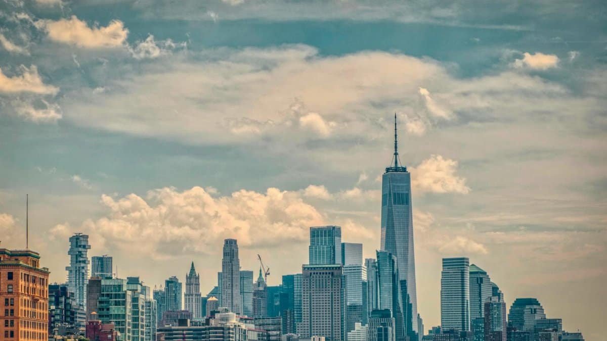 Breathtaking view of New York City skyline featuring One World Trade Center against a cloudy sky.